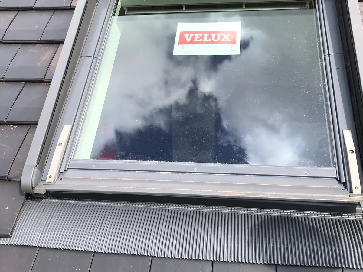 Fenêtre de toit Velux posée sur une toiture en ardoises, avec son raccord d’étanchéité