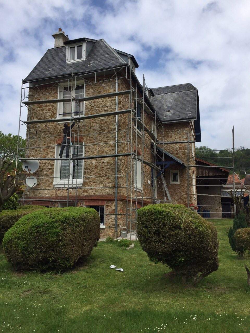 Maison en meulière échafaudée pour la rénovation de sa toiture